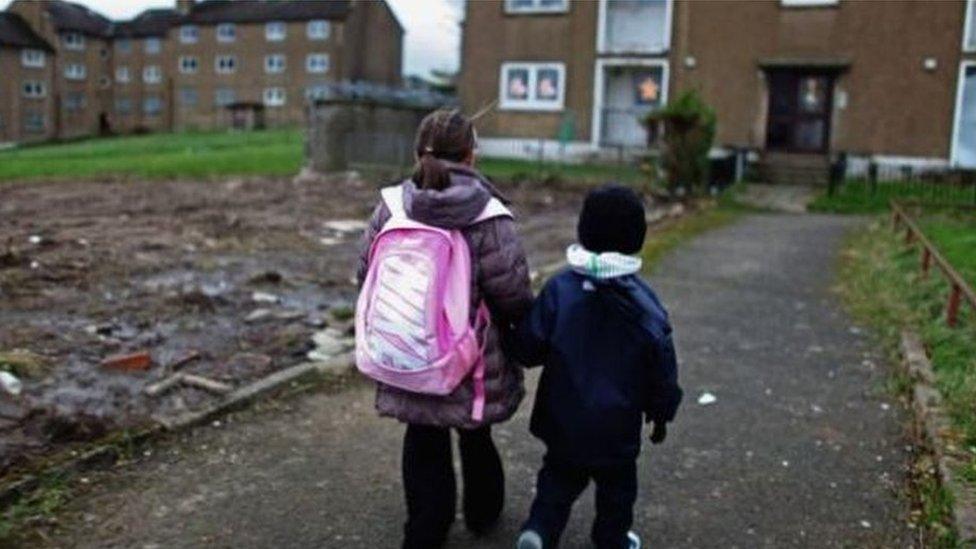 Two children walking towards a housing estate