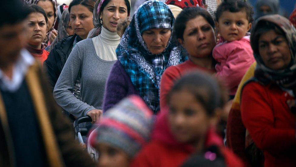 Migrants and refugees line up for a milk distribution at a makeshift camp at the northern Greek border point of Idomeni, Greece