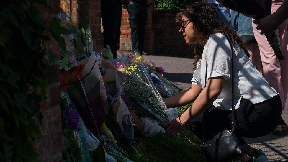 A woman lays flowers outside The Holt School