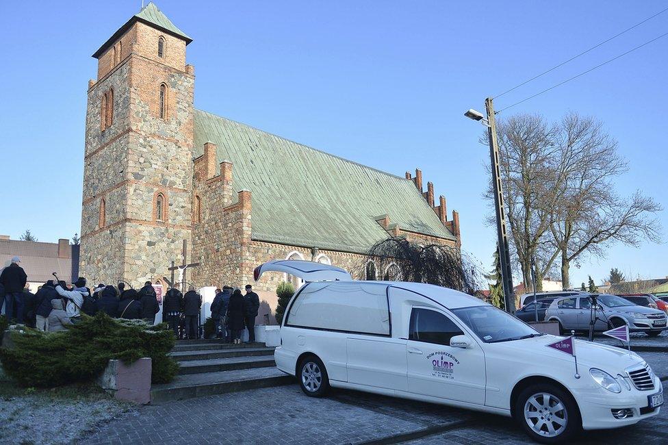 People gather in front of the church for the funeral Mass of Polish truck driver Lukasz Urban in Banie, Poland, 30 December