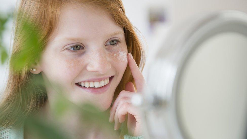 Girl putting face cream on