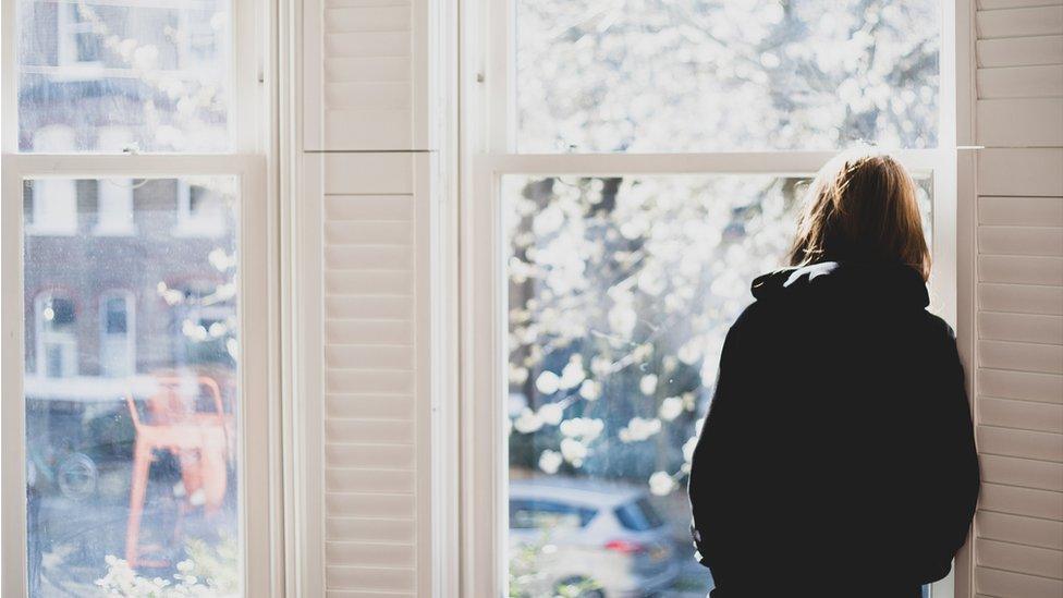 Woman standing and looking out of a window