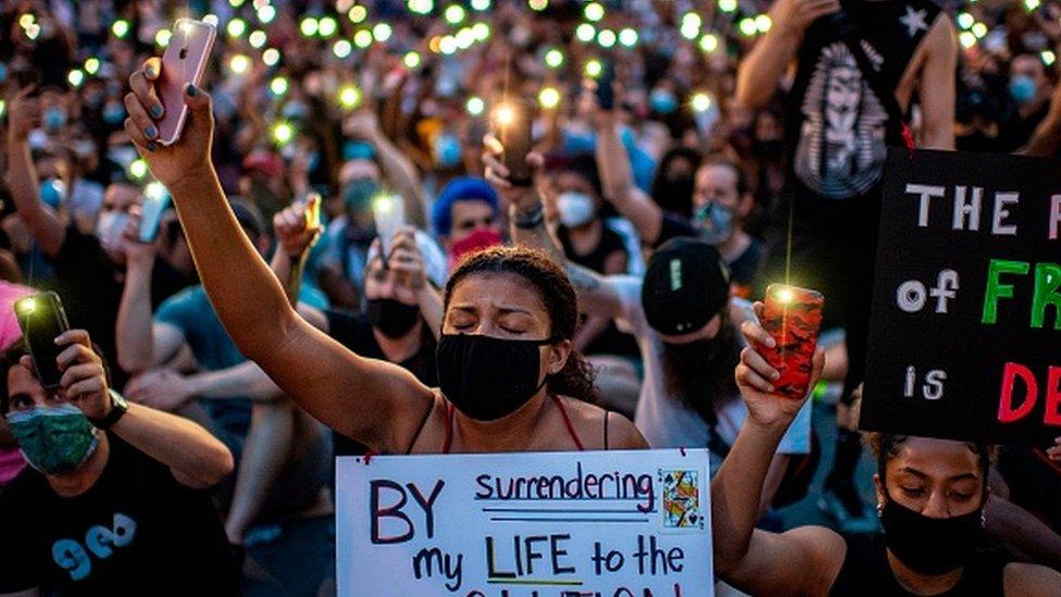 Protesters hold up their phones during a demonstration over the death of George Floyd