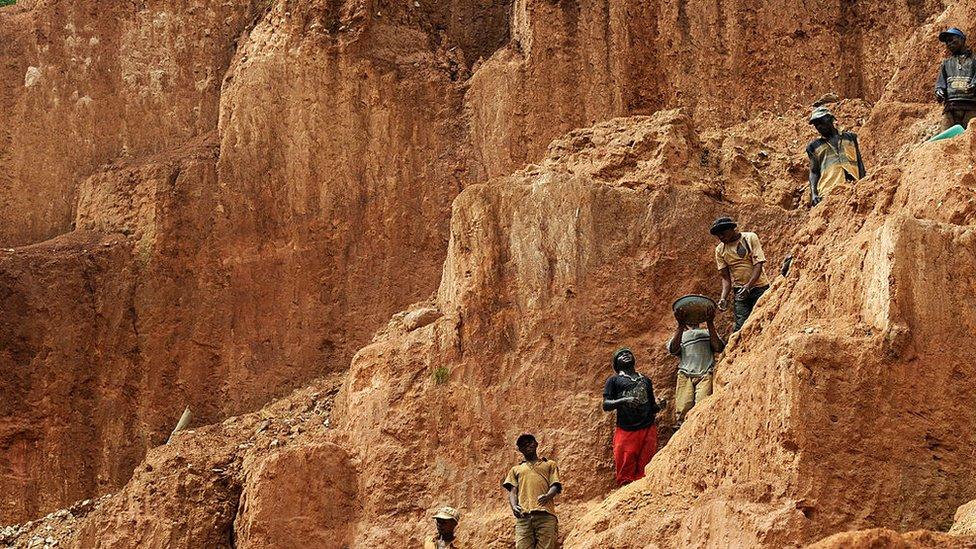 Workers stand on a muddy cliff as they work at a gold mine on February 23, 2009 in Chudja, near Bunia, north eastern Congo. The conflict in the Congo has often been linked to a struggle for control over its minerals resources. The Congo is rich in mineral resources such as gold, diamonds, tin, and cobalt