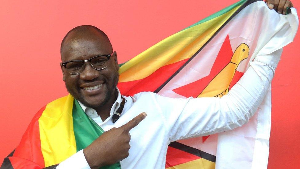 Pastor Evan Mawarire posing with a Zimbabwean flag