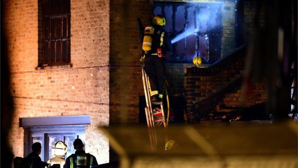 Firefighter aiming hose at burned-out window