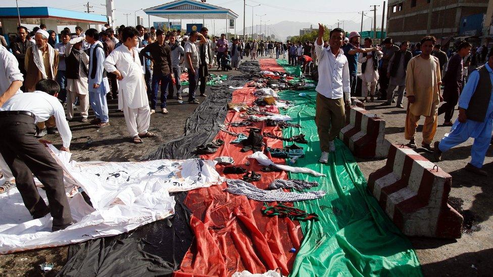 People collect belongings of victims at scene of suicide bomb attack in Kabul. 23 July 2016