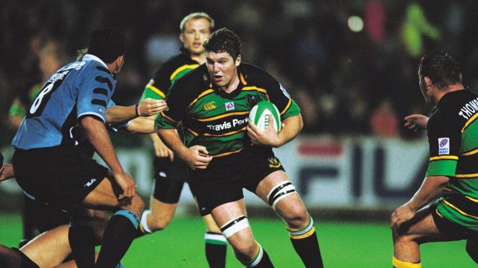 Man in green, black and gold Saints strip runs with the ball past a Cardiff player