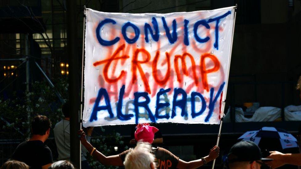 A woman holds a banner in front of New York criminal court