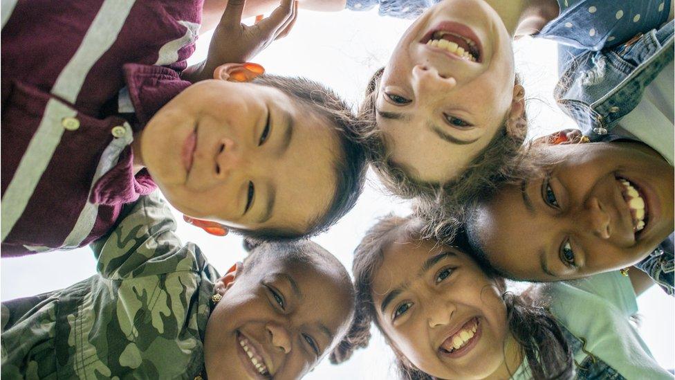 group of children with their heads together.