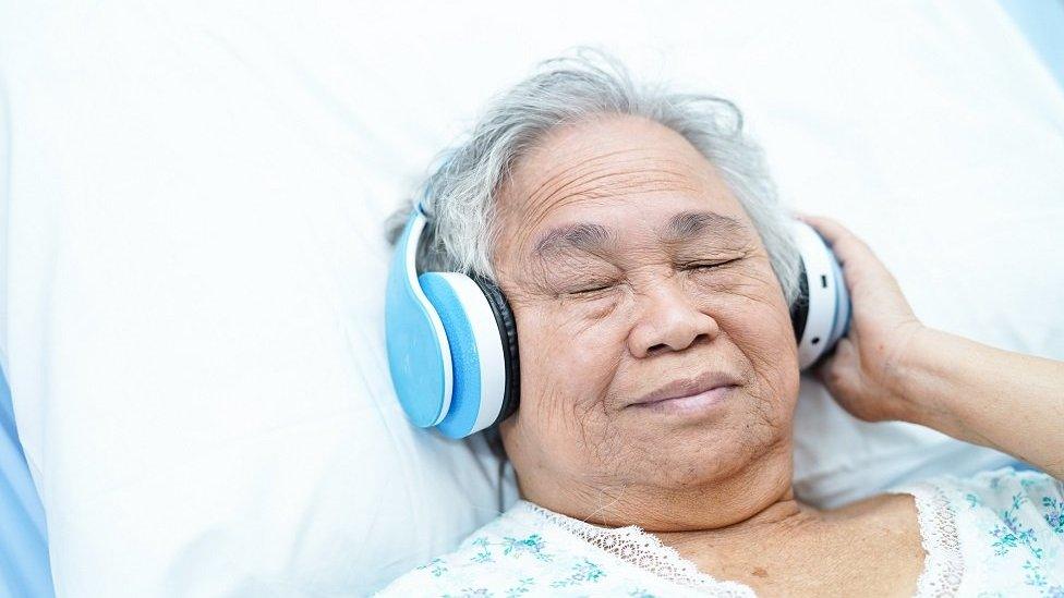 Woman in hospital bed wearing headphones