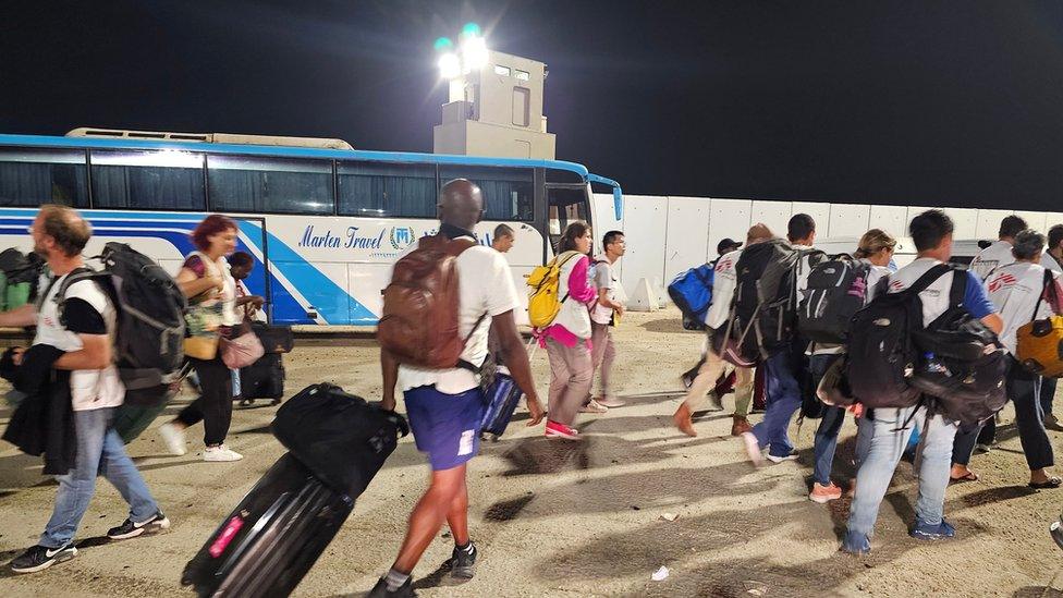 Several foreign nationals walk after passing the Rafah border crossing between the Gaza Strip and Egypt