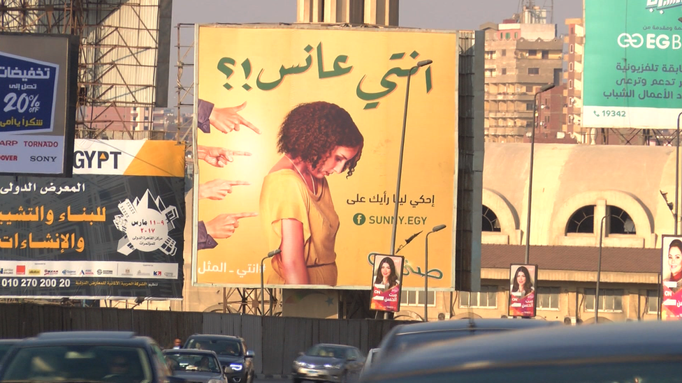 The billboard with a young woman being pointed at, which asks: Are you a spinster?