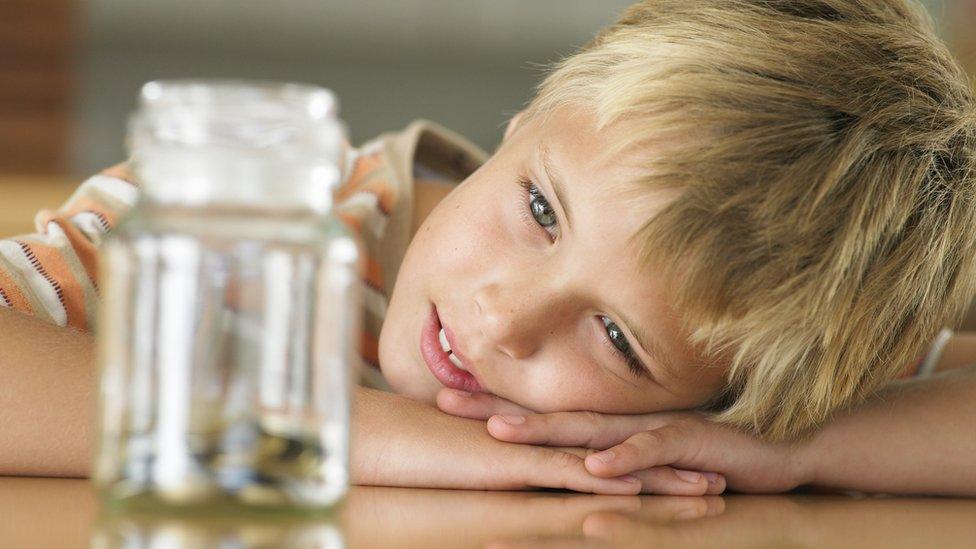 Boy looks at money jar