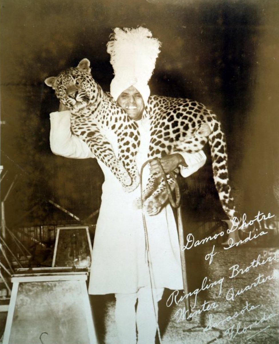 Damoo Dhotre posing for a photograph carrying a leopard