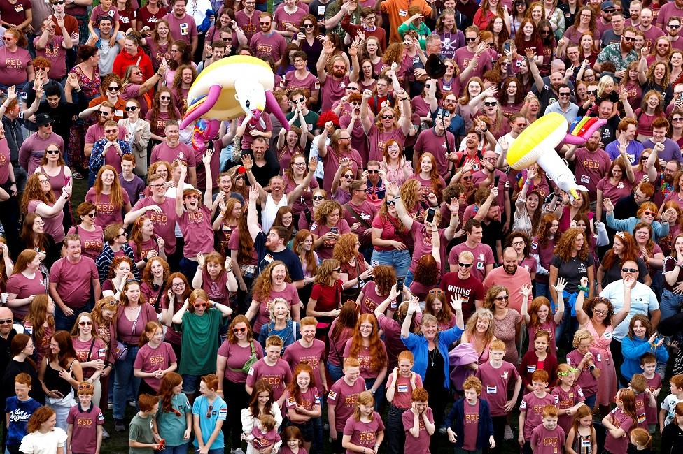 A crowd of people with red hair look up into the camera at the festival