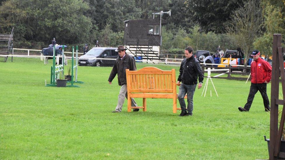 Two men carrying a bench made in memory of Bradley John