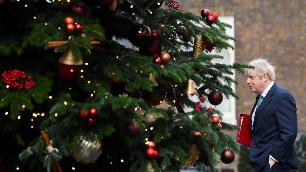 Boris Johnson walks past the Downing Street Christmas tree as he returns to No 10 after a cabinet meeting at the Foreign and Commonwealth Office