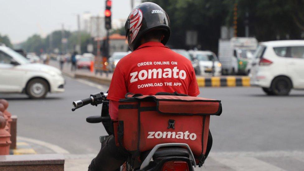 A Zomato delivery boy waits at traffic signal in New Delhi