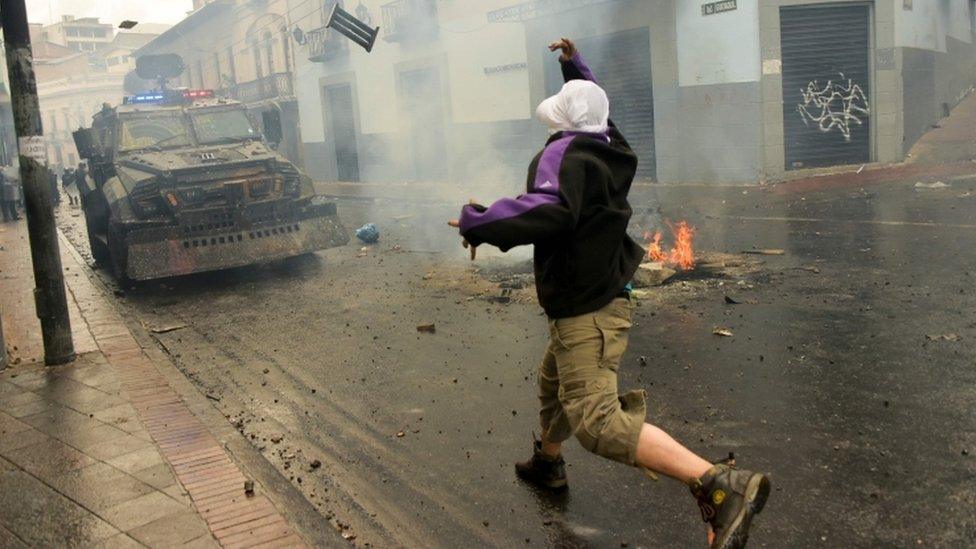 A demonstrator clashes with riot police during a transport strike in Ecuador