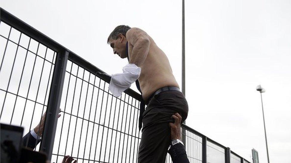 Human Resources Director of Air France, Xavier Broseta, shirtless, tries to cross a fence