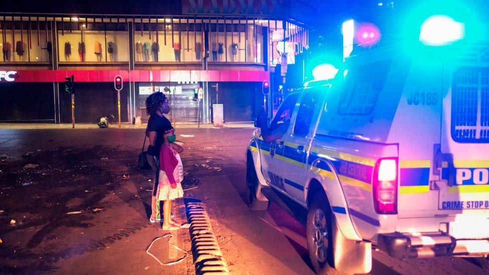 A woman and a child explain to a South African Police Service (SAPS) officer while they are still on the street during curfew in December 2020