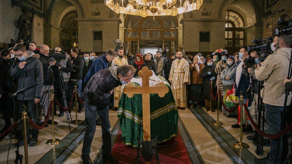 An orthodox faithfhul bends on the cross near the casket of late Serbian patriarch Irinej during his funeral service at Belgrade's cathedral on November 21, 2020 in Belgrade, Serbia.