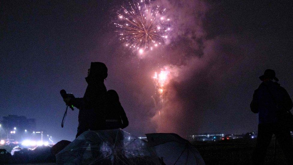 Journalists film as fireworks explode near Tama river in Tokyo