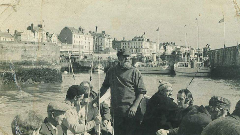 Black and white photograph of local fisherman Leonard Broadbent with a beard, cap and fishing jumper