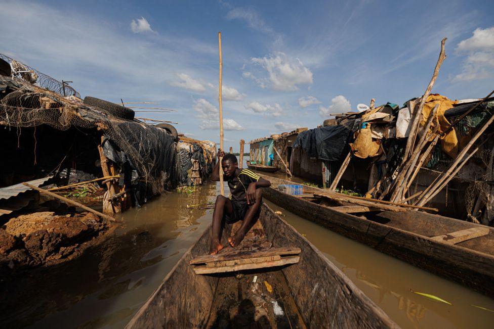 A boy uses a pirogue to move between houses submerged in water in the flooded area of the Badalabougou district in Bamako on 3 October, 2024. 