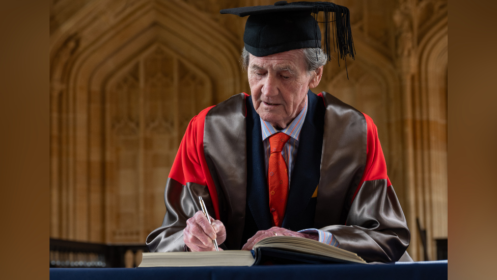 Lord Melvyn Bragg signs a book during Oxford University's annual Encaenia Ceremony, where award honorary degrees are awarded.