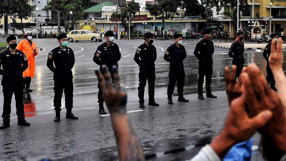 Pro-democracy protesters give the three-fingered salute as the royal motorcade passes in Bangkok, 13 October 2020