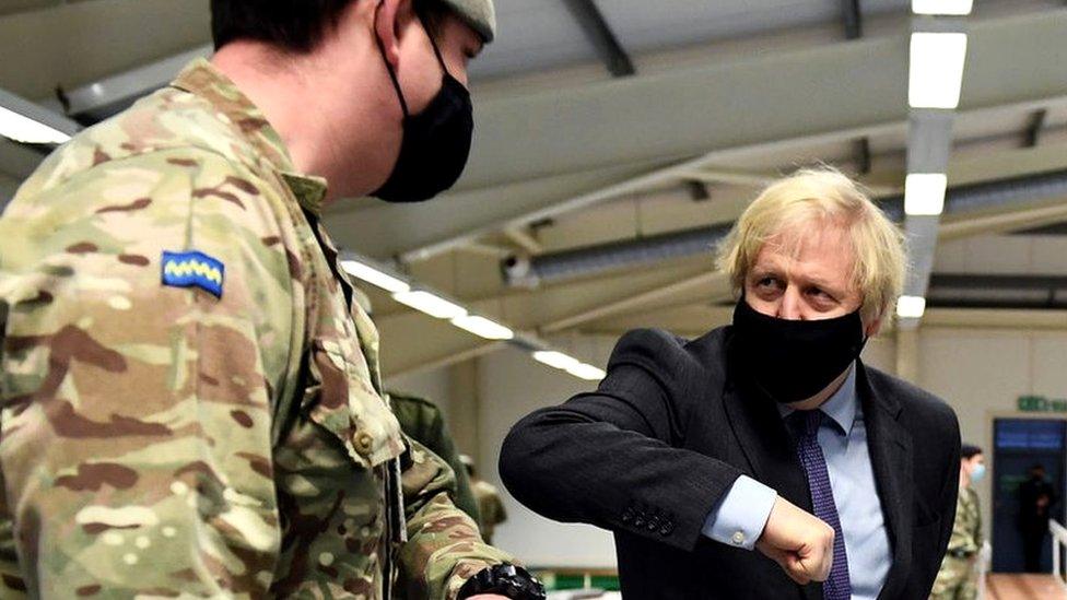 Boris Johnson elbow bumps a member of the British Army at a vaccination centre.