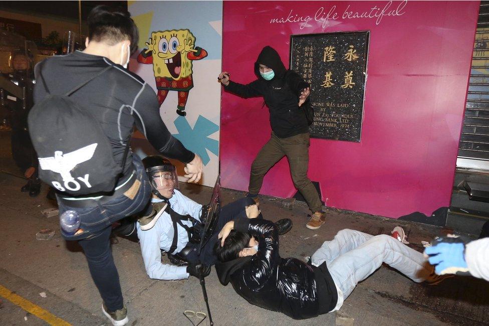 A rioter attacks a police officer on the ground