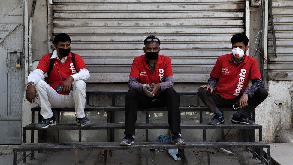 Zomato Food Delivery boys wearing protective masks sit near closed shutters amid Covid-19 (Coronavirus) lock down in Gurugram on the Outskirts of New Delhi, India on 07 April 2020.