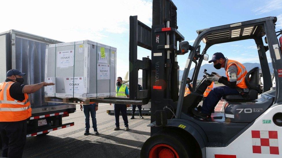 Workers load a container holding doses of the AstraZeneca's vaccine