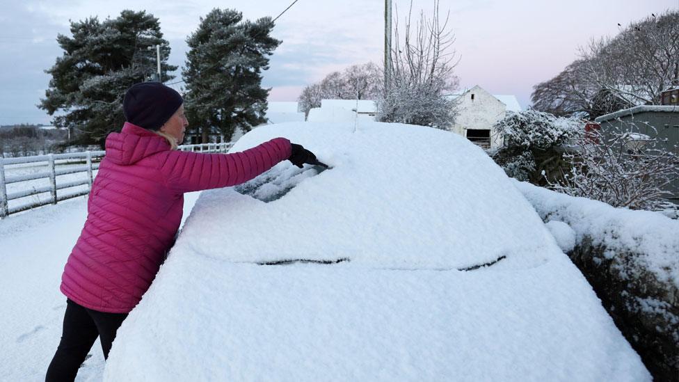 Woman tries to scrape car windscreen in Teesdale, County Durham