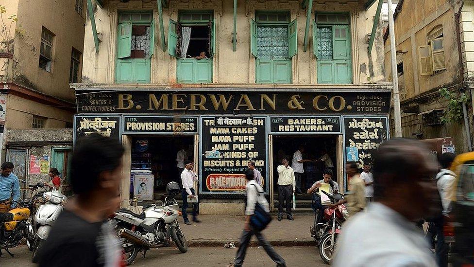 Indian pedestrians walk past the B. Merwan & Co. Irani cafe in Mumbai