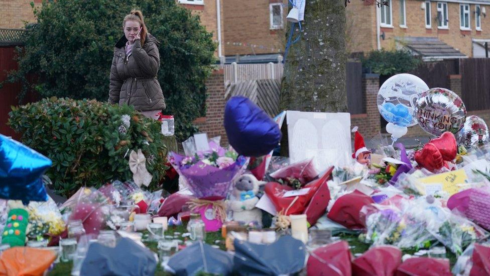 A woman lays flowers among the tribute left near the park in Kingshurst