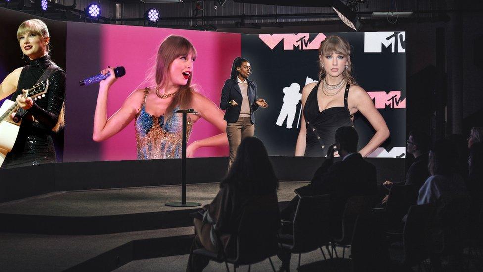 Someone giving a talk with pictures of Taylor behind them