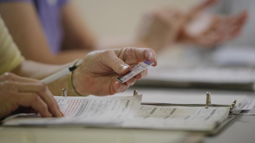 An election worker checks a voter's drivers license