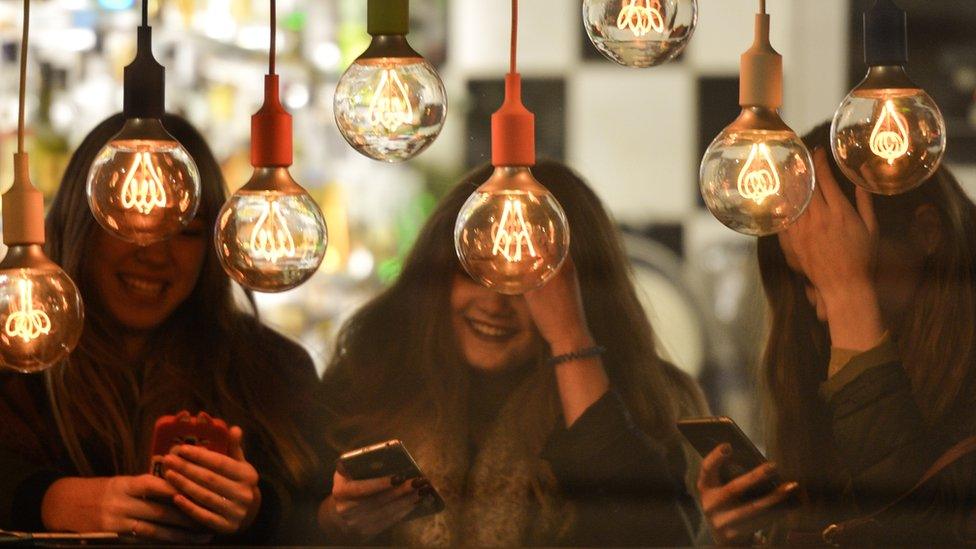 Three girls on their phones in a bar