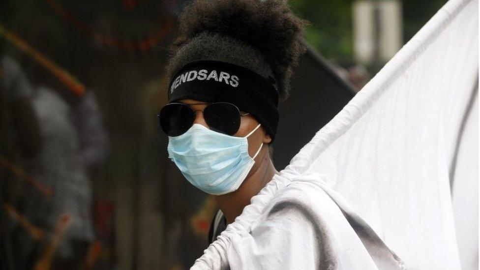 A protester wears a face mask and a head band with the inscription "End SARS" as she stands on the Lagos-Abeokuta expressway during a protest against the Nigeria rogue police, otherwise know as Special Anti-Robbery Squad (SARS), in Ikeja district of Lagos, Nigeria, 19 October 2020