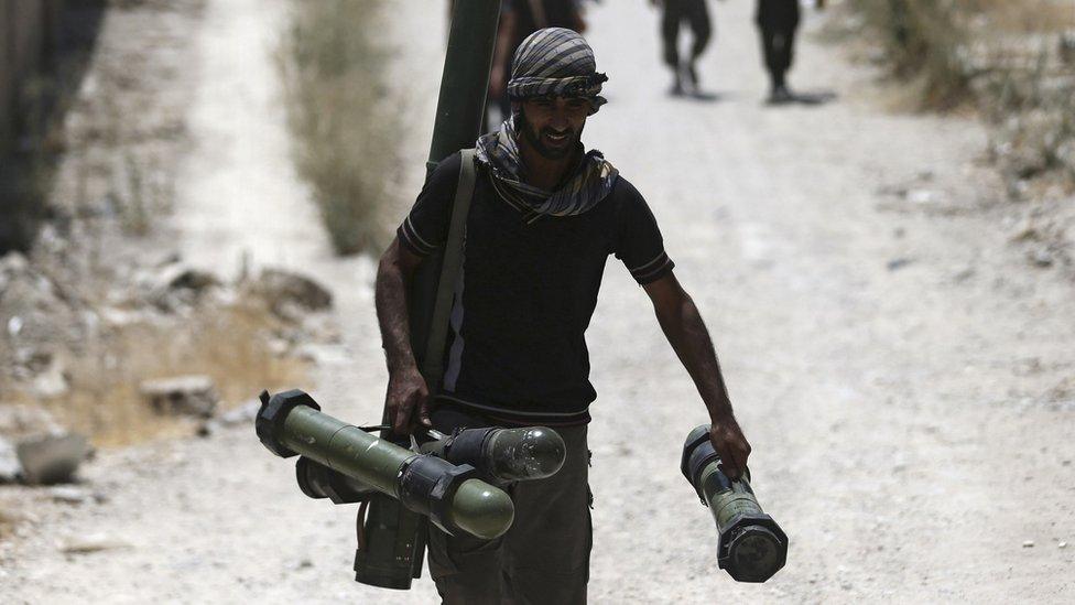 File photo of Free Syrian Army" fighter carrying a weapon as he walks towards his position on the frontline against the forces of Syria"s President Assad in Jobar, a suburb of Damascus