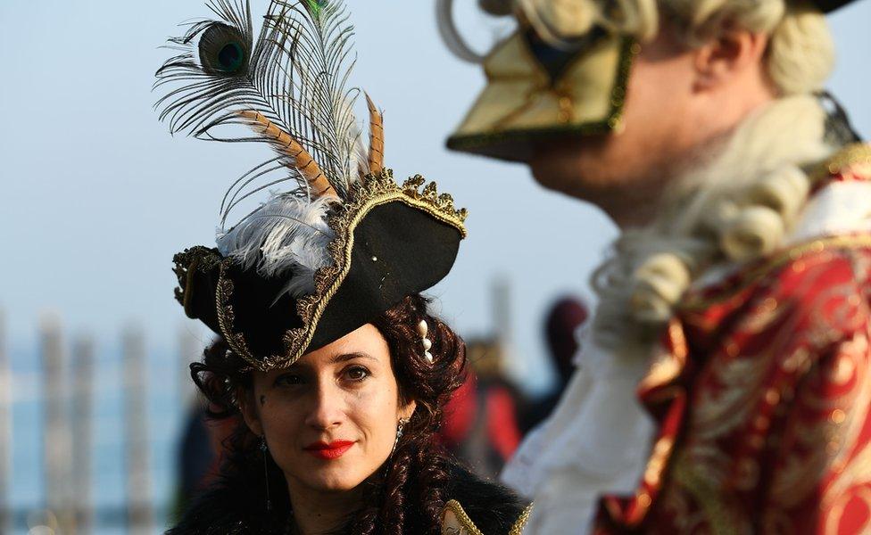 A woman looks at a masked man during the Venice carnival