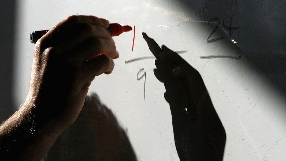 Teacher's hand writing on white board