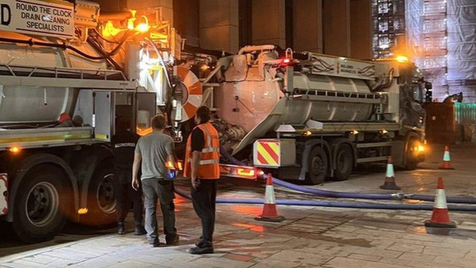 Tankers with flashing lights parked outside the building at night