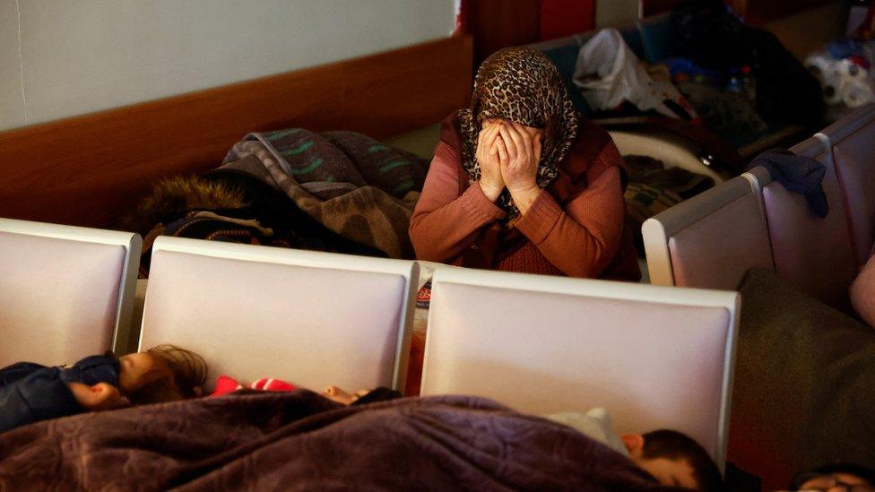 Survivors rest while a woman reacts at a hospital in the aftermath of an earthquake, in Kahramanmaras, Turkey