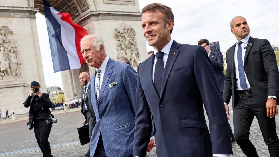 King Charles III and French President Emmanuel Macron walk in front of the Arc de Triomphe in Paris