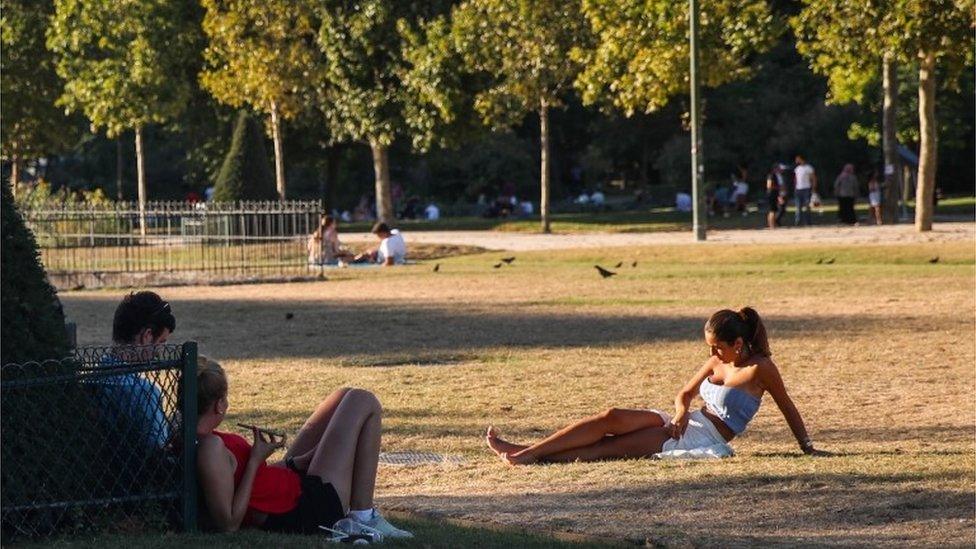 A woman basks in the sun at the Champ de Mars park, next to Eiffel Tower, as the temperature of Paris reaches up to 36-celsius degrees, in Paris, France, 07 August 2020